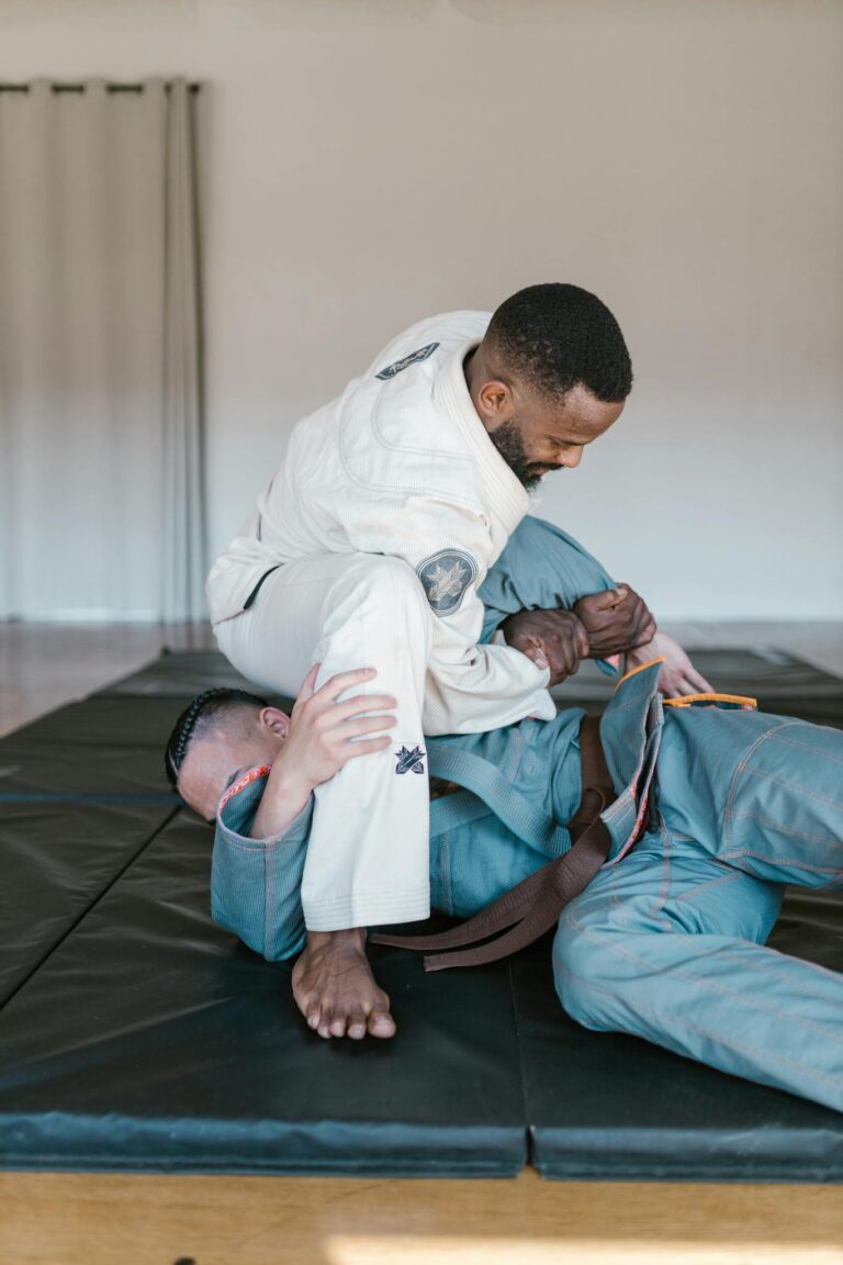 Two men engaged in a martial arts sparring session indoors, showcasing skill and technique.